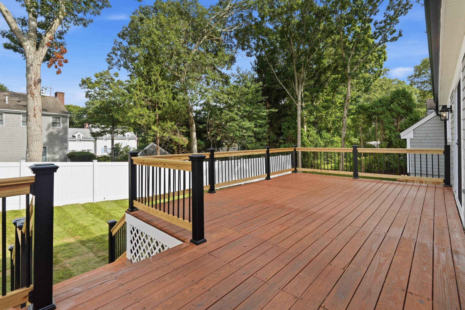 Spacious rear deck overlooking a level fenced yard