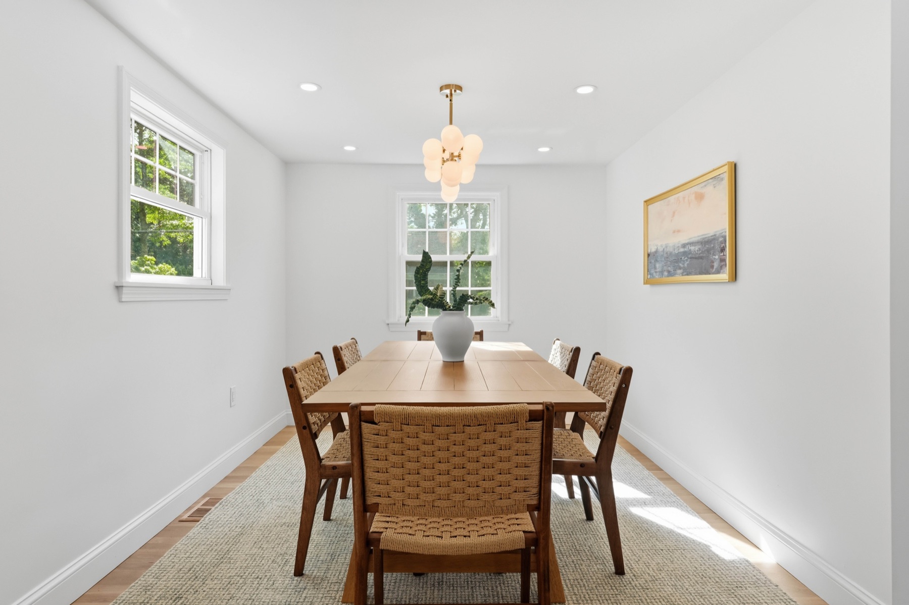 Bright dining room with woven chairs and a sculptural pendant