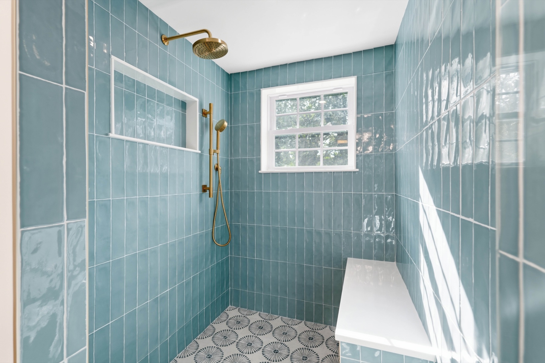 Primary shower with blue tile and brass fixtures